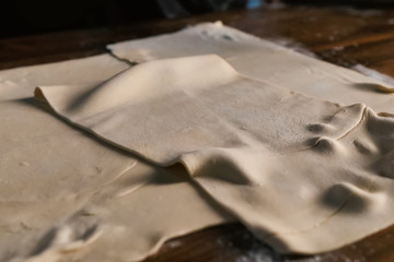 rolling out the dough with rolling pin on the table.