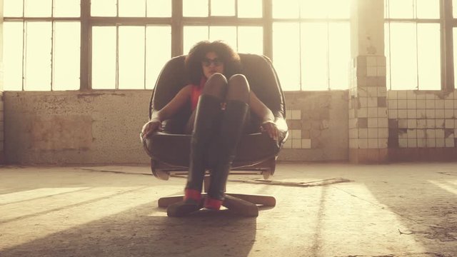Sexy woman sits in a chair in the rays of light