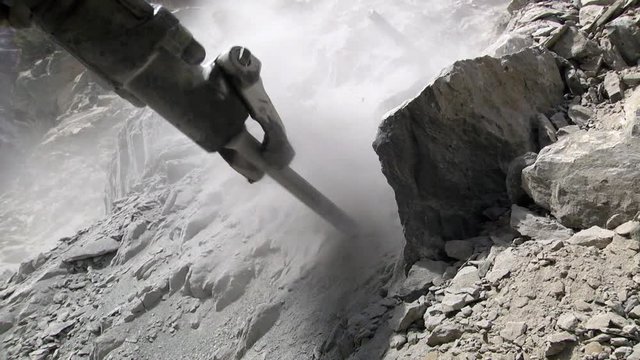 Close up shot of a pneumatic rotary hammer rock drill being used. Eye level.