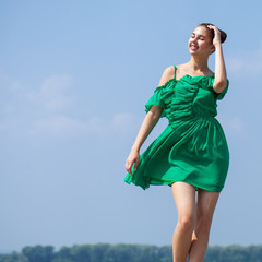 Young beautiful woman in green dress walking on the summer street