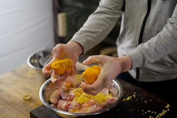 Squeezing lemons in a plate with chicken meat. lemon