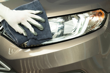 Hand cleaning car with blue micro-fiber cloth.