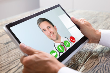 Person Videochatting With Doctor On Digital Tablet