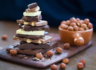 The different grades of chocolate put by the hill on a wooden board, with a filbert on a rusty metal surface. 