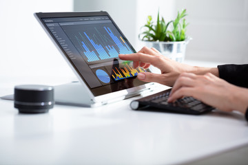 Businesswoman Analyzing Graph On Laptop At Workplace - obrazy, fototapety, plakaty