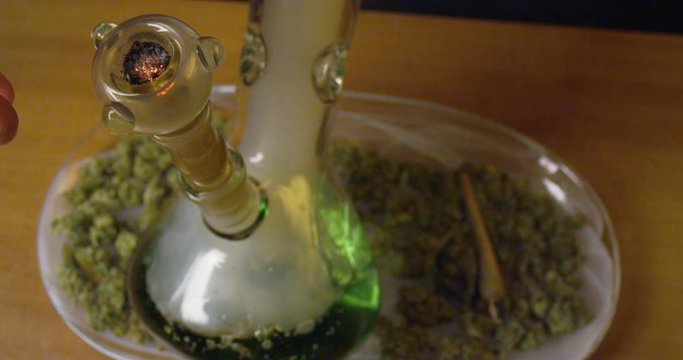 A bowl of marijuana finishes burning and is pulled from a large bong, as the smoke is inhaled - extreme closeup - slow motion - shot on RED