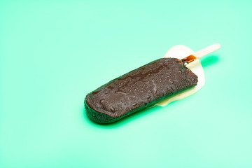 chocolate outer popsicle in a melting process on light green background
