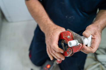 Close up on hands of plumber cutting plastic pipes cut white plumbing installation craftsman at work