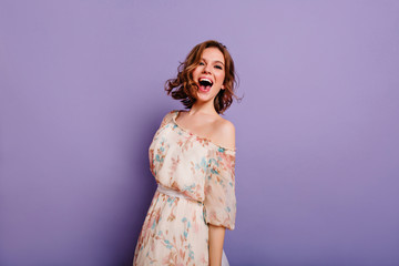 Sensual white woman in summer dress laughing on purple background. Charming female model in...