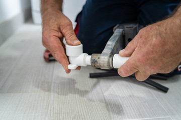 Close up on hands of plumber welding plastic pipes plumbing installation