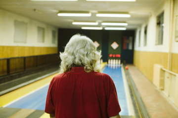 An older man bowling in a bowling alley