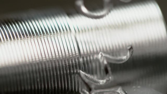 SLOW MOTION, MACRO, DOF: Twisted shavings break off the aluminium workpiece during threading process. Large industrial lathe tool shaving grooves into a metal rod. Detailed shot of bolt manufacture.
