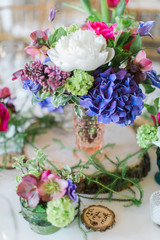 Colorful wedding arrangements on table, white peonies, blue and hot pink flowers, reception decor, bohemian table flowers