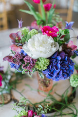 Colorful wedding arrangements on table, white peonies, blue and hot pink flowers, reception decor, bohemian table flowers