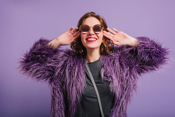 Studio shot of fascinating young woman with short hair laughing on purple background. Indoor...