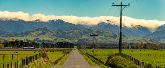 Rural road from the Eastern hills to the cloud covered Tararua ranges in Wairarapa New Zealand - Powered by Adobe