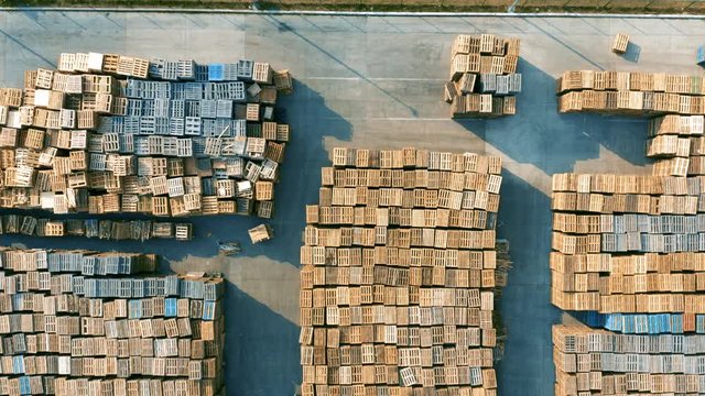 Aerial top view of a storage yard (open storage) of wood pallets with working forklifts and stockmans