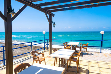 Island of Cyprus. Cafe on the Mediterranean sea. Tables near the sea. Holidays in Cyprus. Turquoise water. Pebbles on the beach. Lunch with sea view.