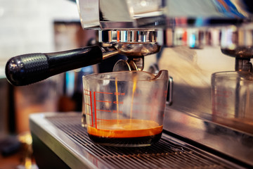Espresso pouring coffee in the measuring cup. selective focus and blur background.