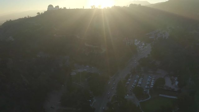 Aerial, reverse, drone shot, of the Griffith park and the observatory, on a hill, on a sunny, summer evening, in Hollywood, Los Angeles, USA