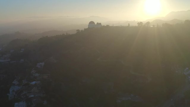 Aerial, tracking, drone shot, around the Griffith park, overlooking a observatory, on a hill, on a sunny, summer evening, in Hollywood, Los Angeles, USA