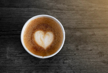 Heart, hot coffee latte in paper cup on black wood background, Top view, copy space.