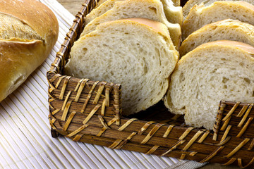 closeup of bread basket and lode of italian bread on wooden table