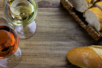 white wine glass and rose wine glass on wooden table with bread basket top down view