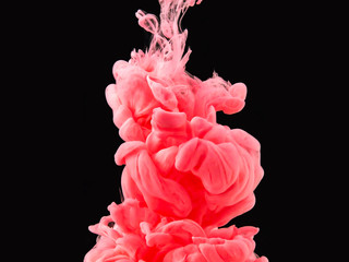 Pink-red acrylic smoke under water, isolated on black background, close up view. Drop of paint swirling underwater. Abstract background for overlays design, screen blending mode layer