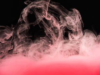 Drop of pink paint dissolving into liquid, isolated on black background, close up view. Pink...