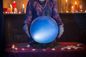 Hands of fortune teller with illuminated crystal ball