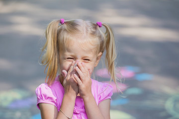 little girl draws with chalk on  pavement