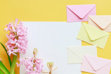 Colorful envelopes and hyacinth flowers on yellow background