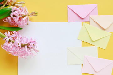 Colorful envelopes and hyacinth flowers on yellow background