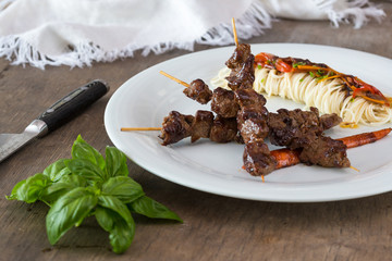 Asian style grilled teriyaki beef skewers on a white plate, top view. Delicious appetizer