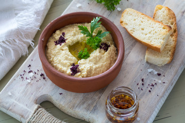 A close-up of a colorful snack composition on a wooden background. Delicious hummus in glass bowl and on a wooden plate.