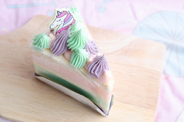 Unicorn rainbow cake on wooden plate on pink background