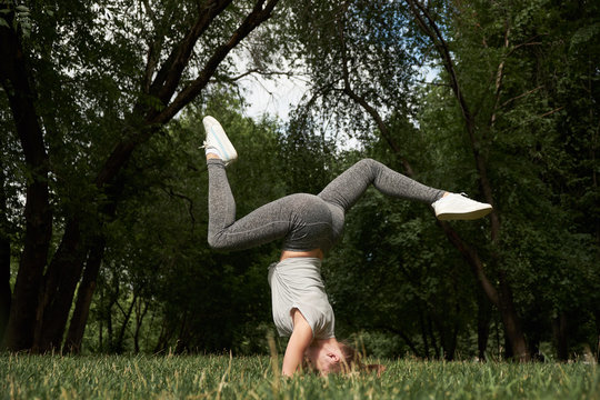 Beautiful sporty fit yogi woman practices yoga handstand asana Bhuja Vrischikasana - Scorpion handstand pose