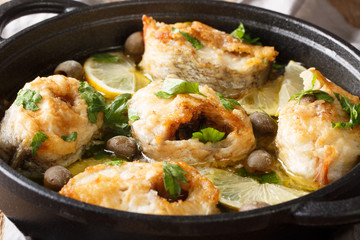 Spicy cod steaks baked with lemon and olives closeup in a pan. horizontal