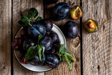 Colander with ripe juicy plums on rustic kitchen table. Healthy vegetarian food. Bio, organic eat. Top view. Copy space.