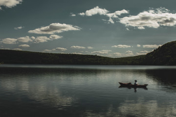 dark artistic picture of Devil's Lake WI , with boat floating on water , long exposure