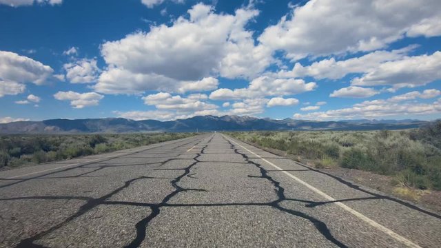 Driving on empty Benton Crossing road over Long Valley Whitmore Hot Springs, Mono County, California. USA.  Traveling through desert road with clouded blue sky.