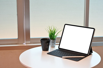 Tablet blank display screen with pencil and coffee on table.