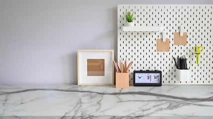 Workspace marble desk with pegboard, photo frame, pencil pot and office supplies.
