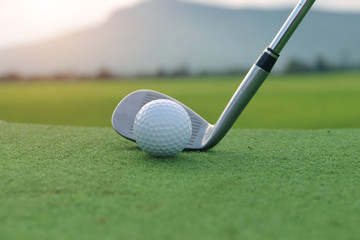 Golf ball and golf club in beautiful golf course at sunset background. Golf ball on green in golf course at Thailand