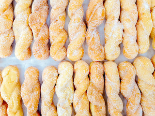 Top view and crop lots of twist doughnut with sugar on bakery paper background. Doughnut is the one causes disease of coronary artery disease and obesity.