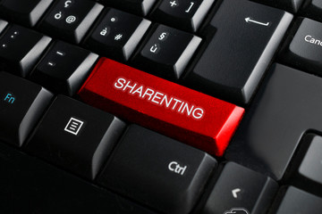 Black keyboard with a red key and the sharenting word - obrazy, fototapety, plakaty