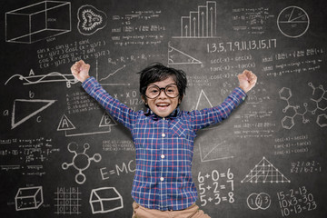 Happy little boy jumping in the classroom