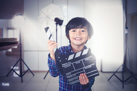 Little boy holds clapperboard during film production