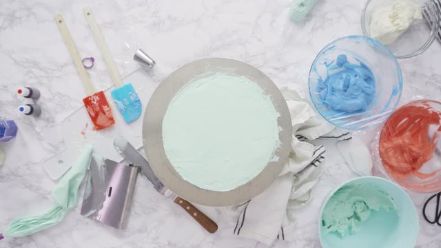 Step by step. Piping buttercream rosettes on top of round three-layer vanilla cake.